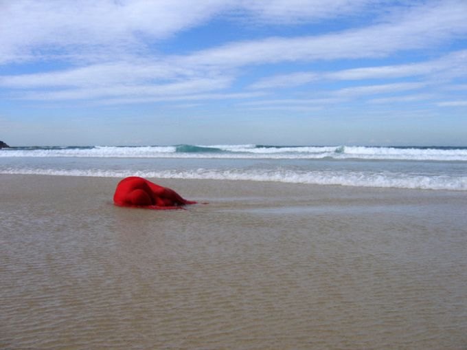 Conversation, 2008, photograph: the artist in red on the shoreline. Shown at Arc One Gallery, Melbourne
