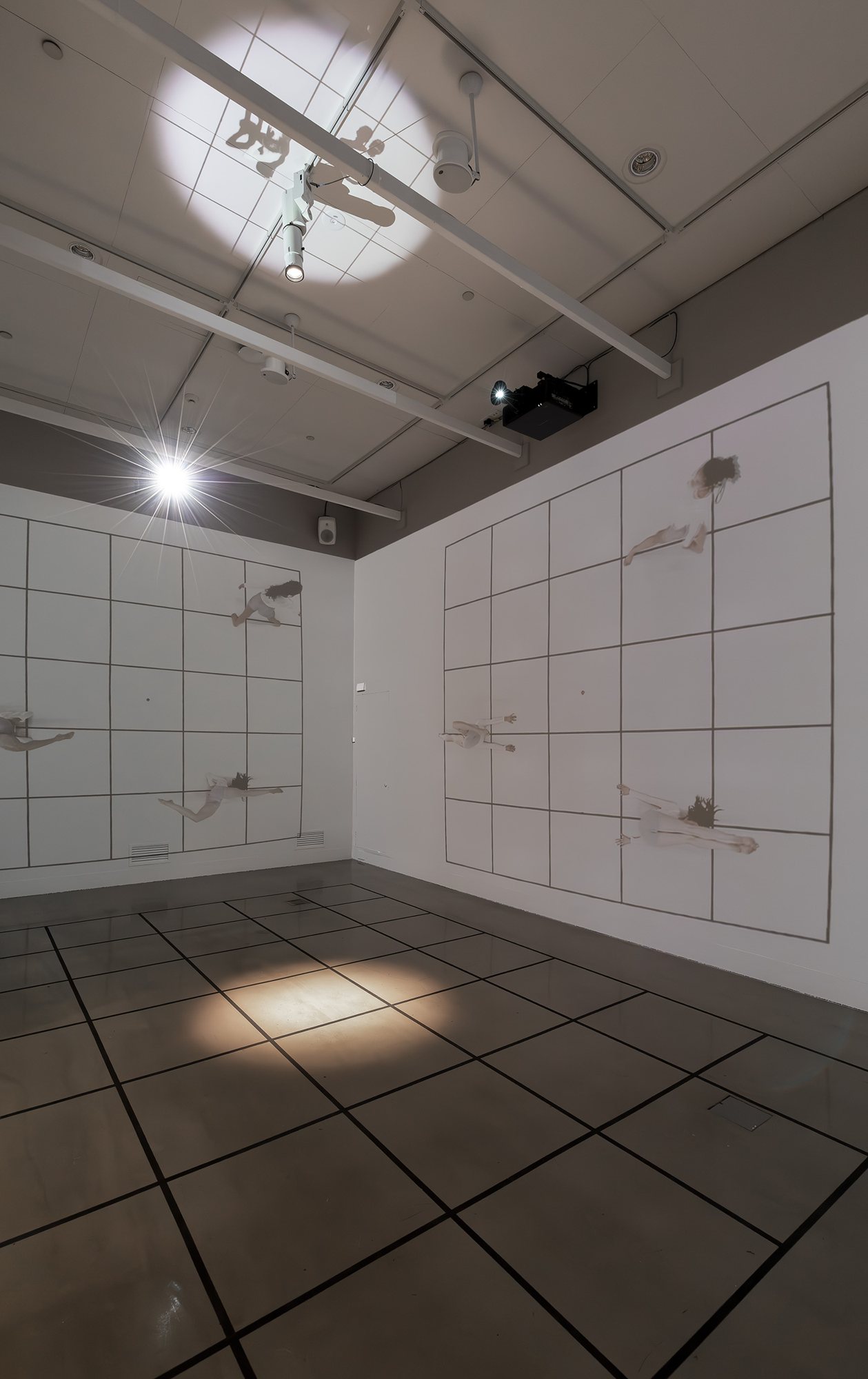 Projector and spotlight above two walls of dancers moving across a grid