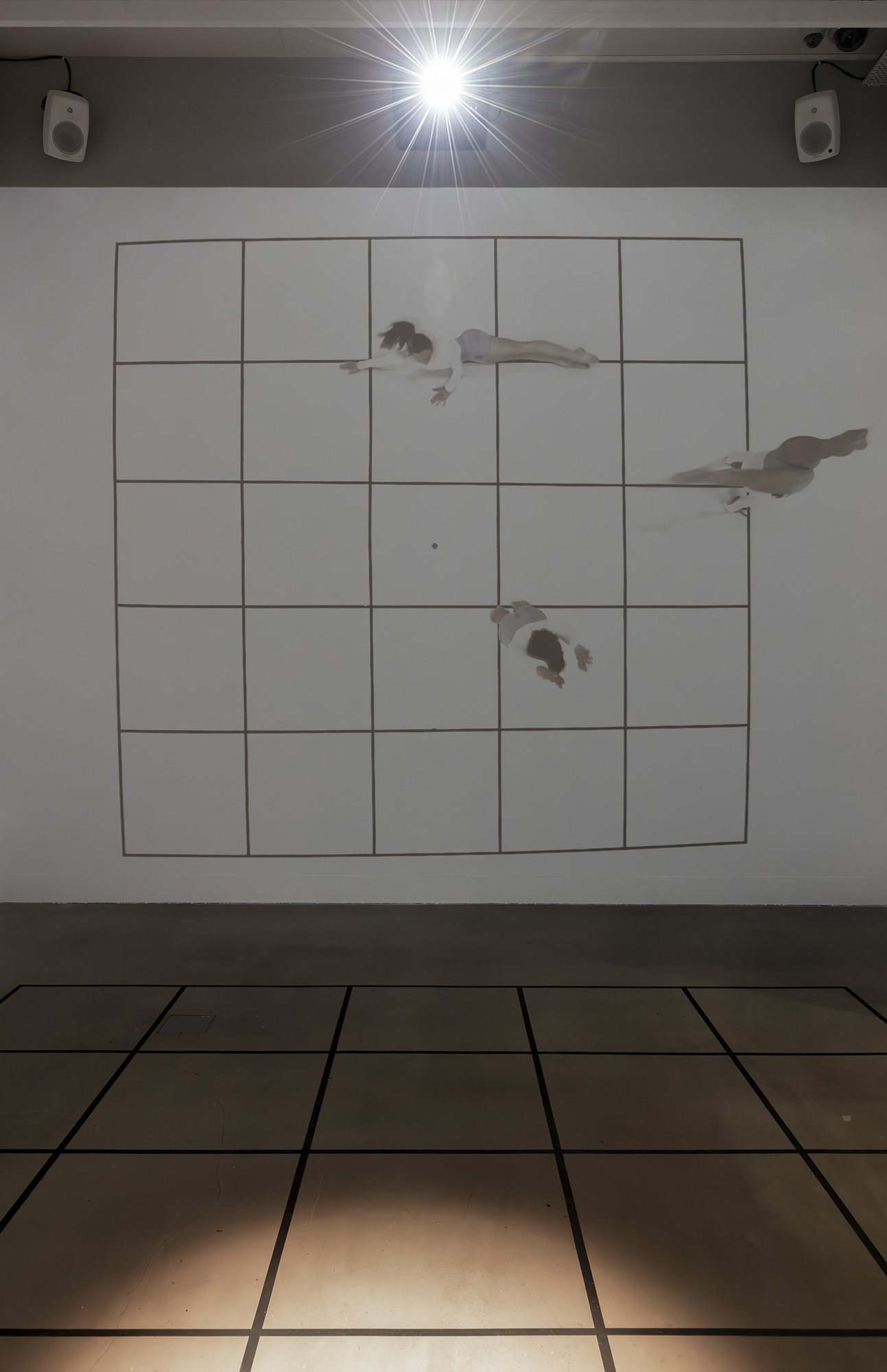 Three dancers seen from above, drifting across a projected grid