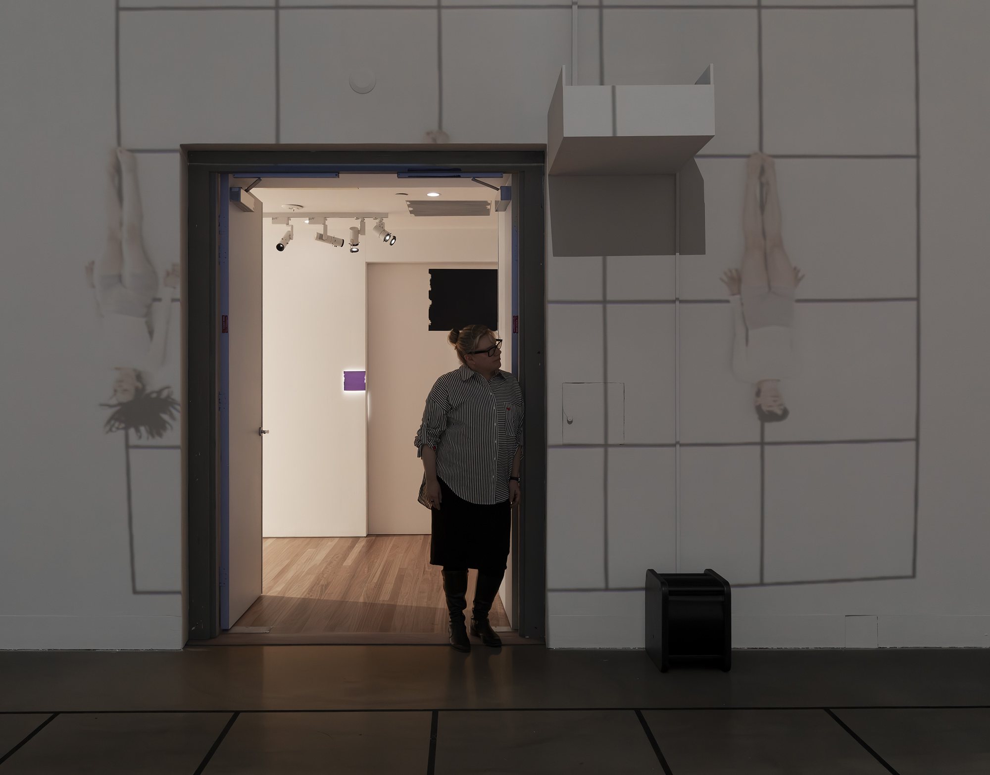 A visitor in the doorway between two upside-down projected dancers