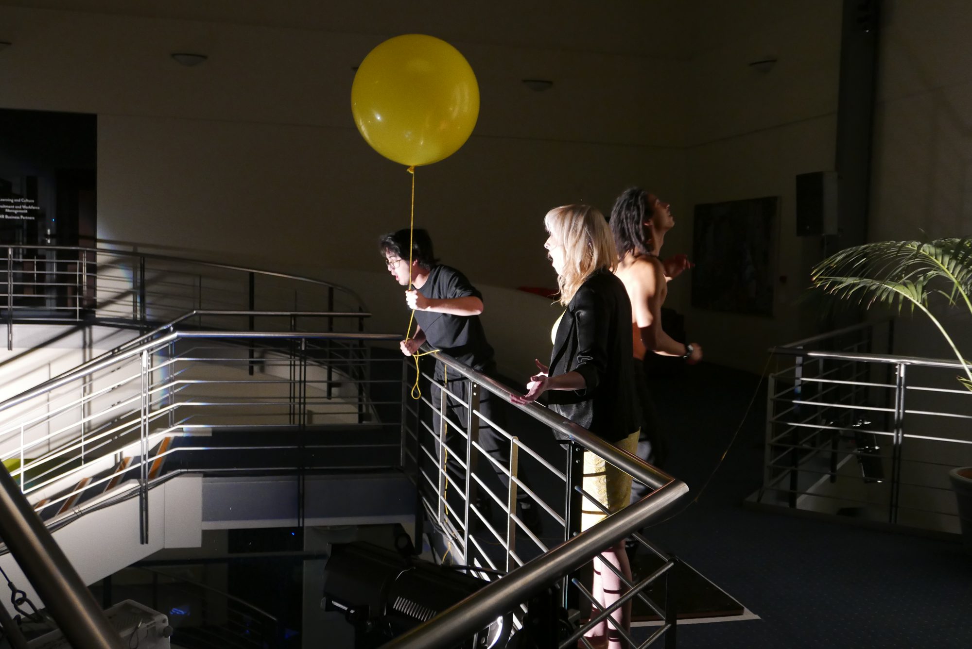 Performers with a large yellow balloon on the atrium stairs