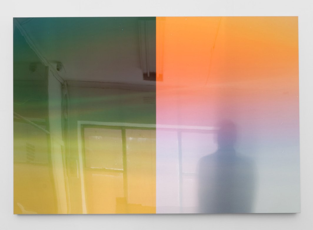 A large photographic print washed in green, yellow, orange and violet light, with the shadow of a figure