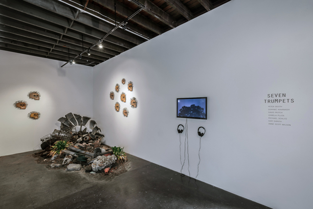 Gallery view with a sculpture on the floor, works on the walls and the video screen at the back