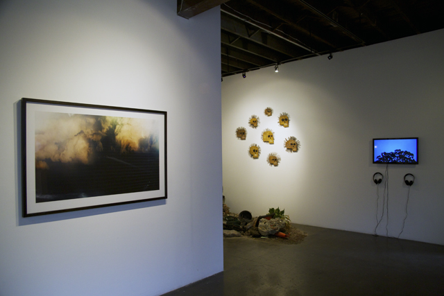 A framed photograph of fire and smoke, with skull works and the video screen beyond